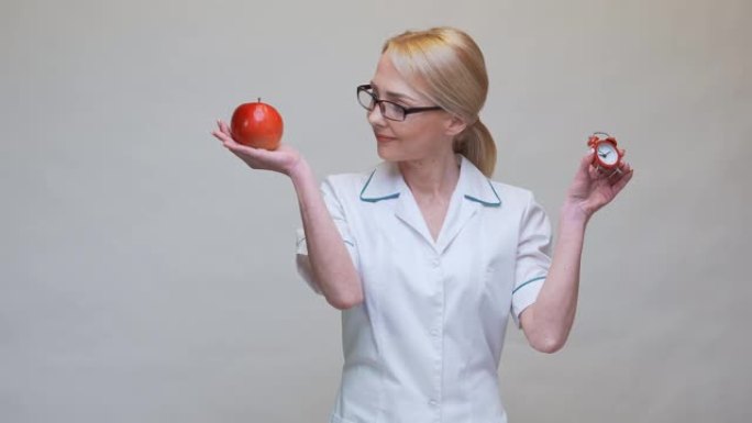 营养师医生健康生活理念 -- 手持有机红苹果和闹钟