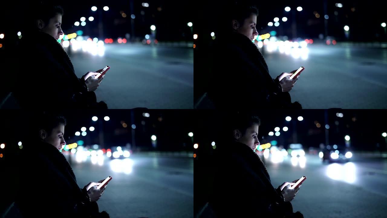 年轻女子拿着手机，在冬天的夜城读一些文字或新闻