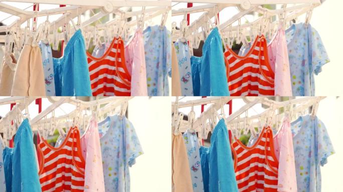 4k拍摄的干燥婴儿彩色衣服挂在户外的夹子上。