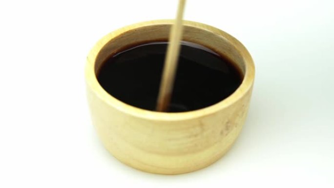 木杯中的黑咖啡和白色背景上的木头制成的咖啡球拍。慢动作。