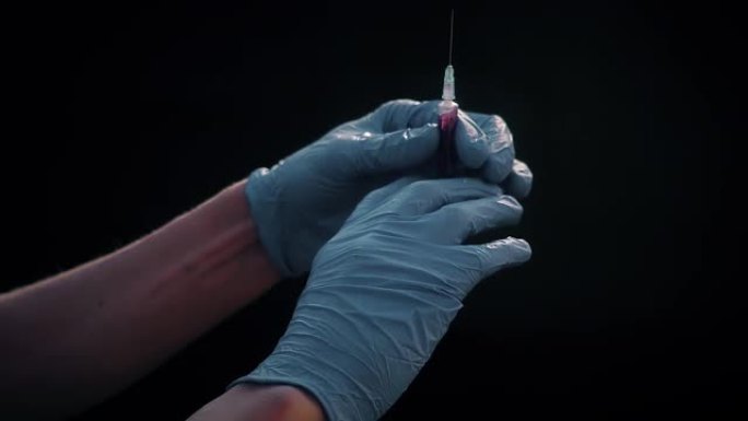 一只戴着蓝色医用手套的手拿着一个注射用的注射器。消除气泡。检查注射器，药物喷射。