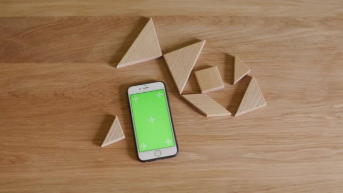 木制桌子木头上的智能手机，带木制七巧板