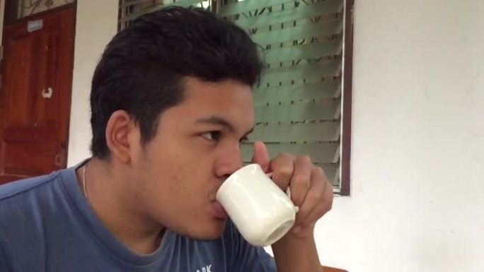 亚洲男子喝白杯咖啡