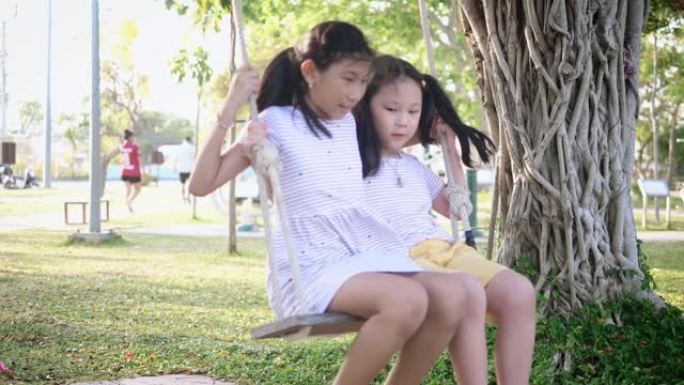 快乐的亚洲女孩一起玩秋千，慢动作。