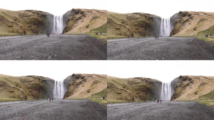 冰岛南部的Skogafoss瀑布，在金环上。游人前来看瀑布，游人在山脚下散步。