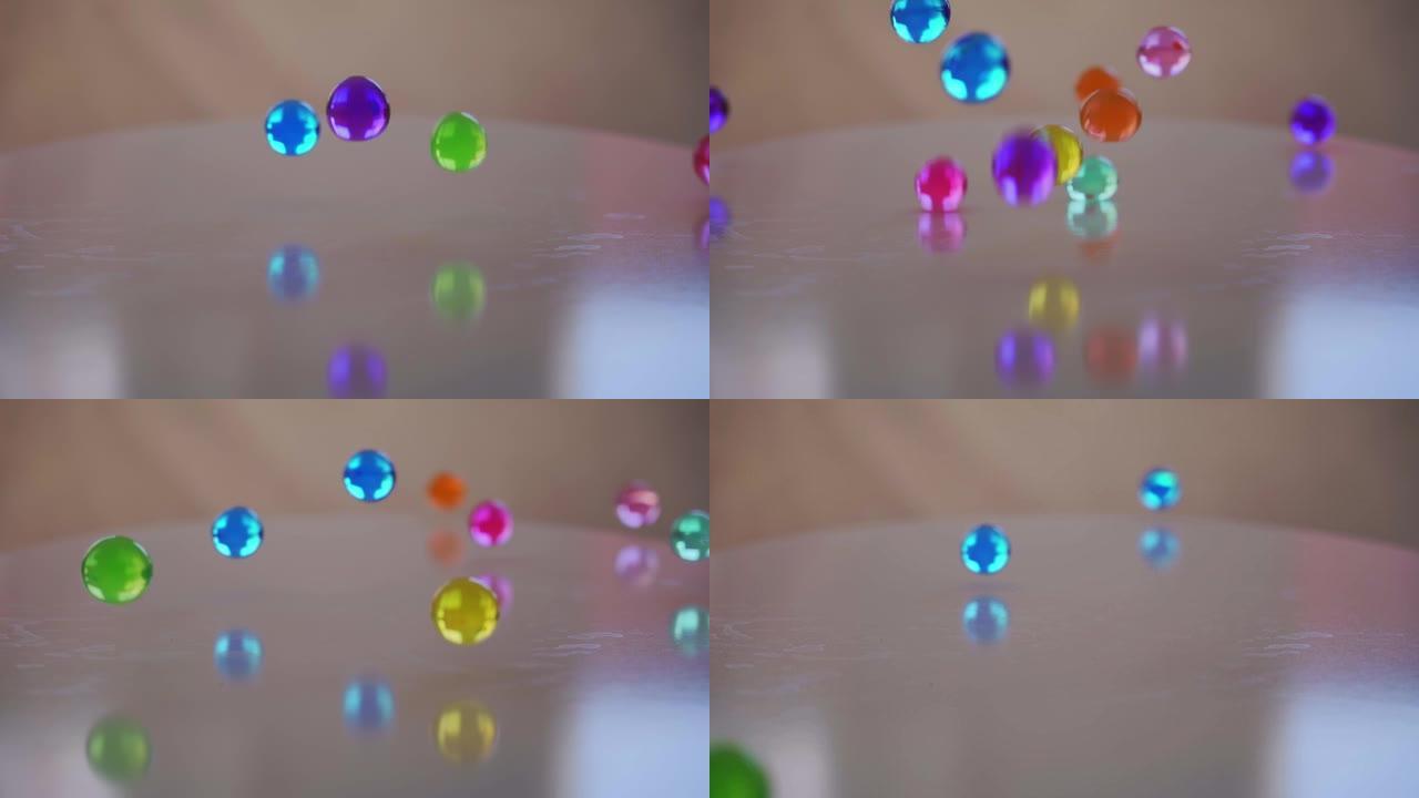 一些五彩缤纷的大聚合物水球的慢动作视频，当您将它们浸入水中时，它们会在几个小时内在白色表面上弹跳，这
