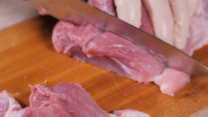 金属刀切肉。在木板上切肉。猪肉在董事会上。猪肉片。库克的手戴着乳胶手套。