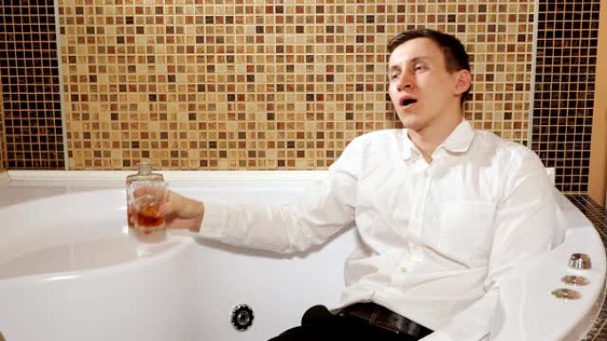 穿着裤子和衬衫的男人躺在浴缸里喝酒
