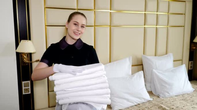 酒店房间准备。女仆在酒店套房里整理，并为居民带来几条干净的新鲜毛巾。微笑的parlormaid手上放