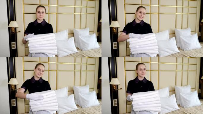 酒店房间准备。女仆在酒店套房里整理，并为居民带来几条干净的新鲜毛巾。微笑的parlormaid手上放