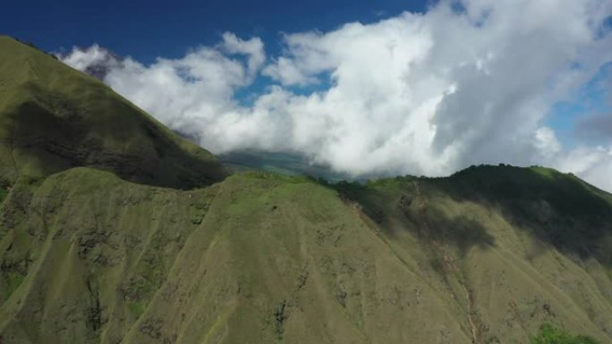 从上方可以看到，令人惊叹的鸟瞰图是绿色的山脉，背景是云彩和美丽的蓝天。印度尼西亚西努沙登加拉省龙目岛