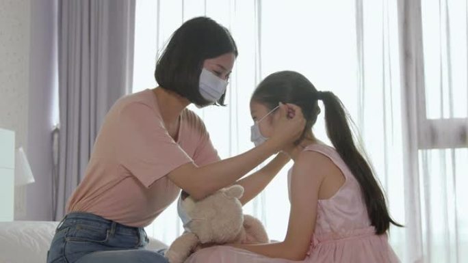 母亲帮助女儿在床上戴医用口罩