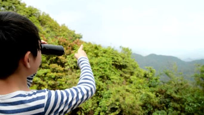 小男孩在山顶上用望远镜看风景