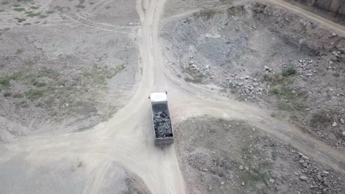 装满碎石的建筑卡车的无人机飞行在一条土路上行驶