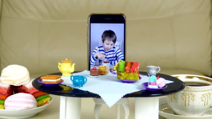 智能手机上的男孩在娃娃桌上喝茶