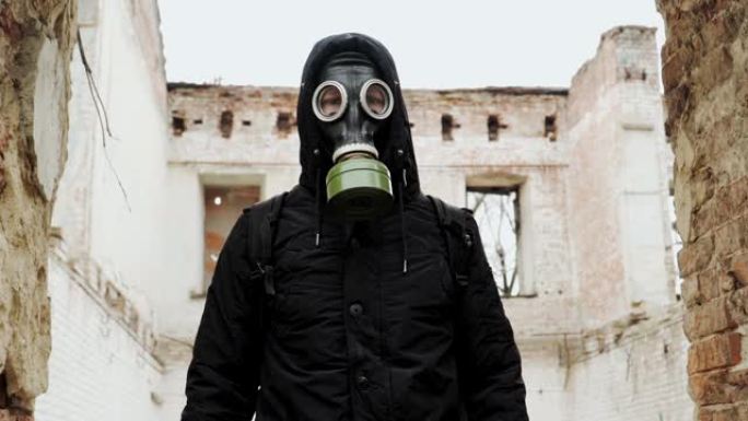 肖像。特写。那个戴着防毒面具和黑色衣服的家伙，背景是一栋废弃的建筑。慢动作。