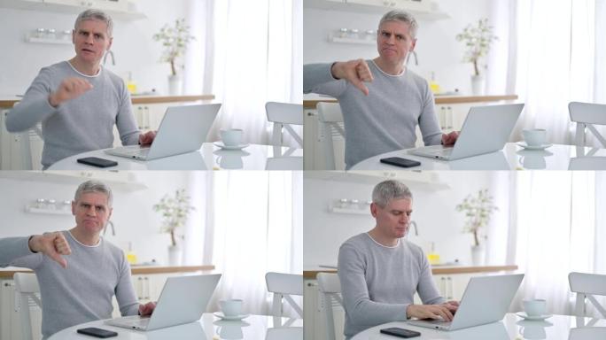 沮丧的高级老人用笔记本电脑做大拇指