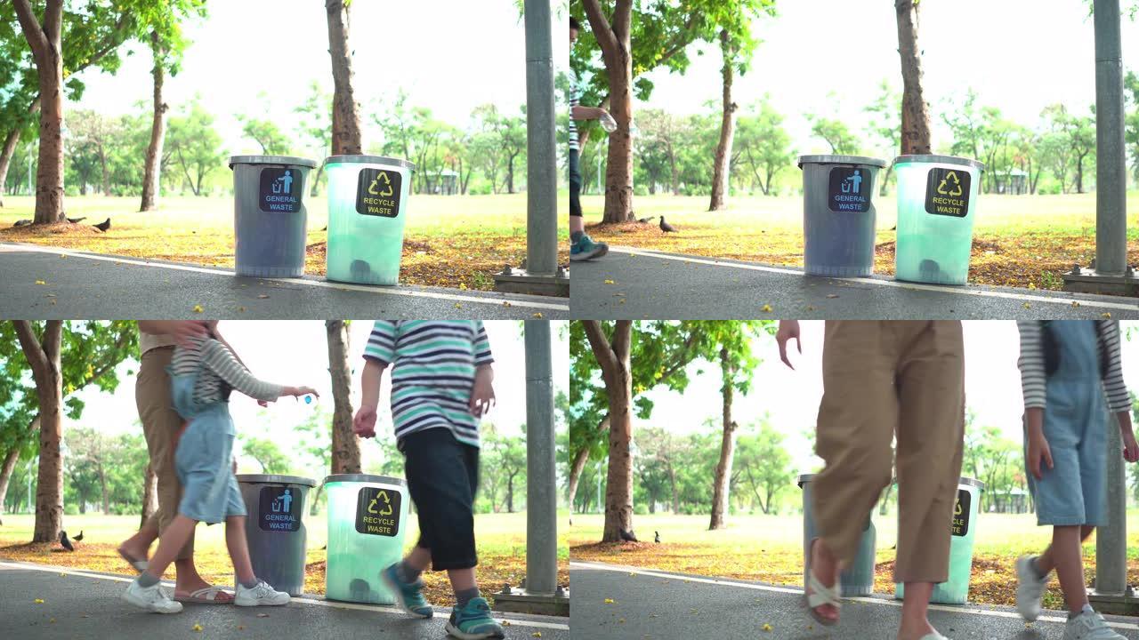 侧视图: 周末阳光明媚的日子，亚洲家庭，母亲，兄弟和姐妹在公园的回收站中步行并分离透明塑料瓶作为回收