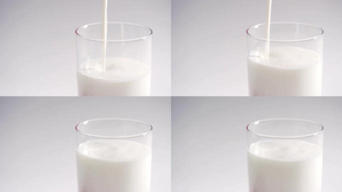 一个人将新鲜的有机酸奶倒入透明玻璃杯中。牛奶酸奶慢慢装满玻璃杯，在白色背景上隔离4k