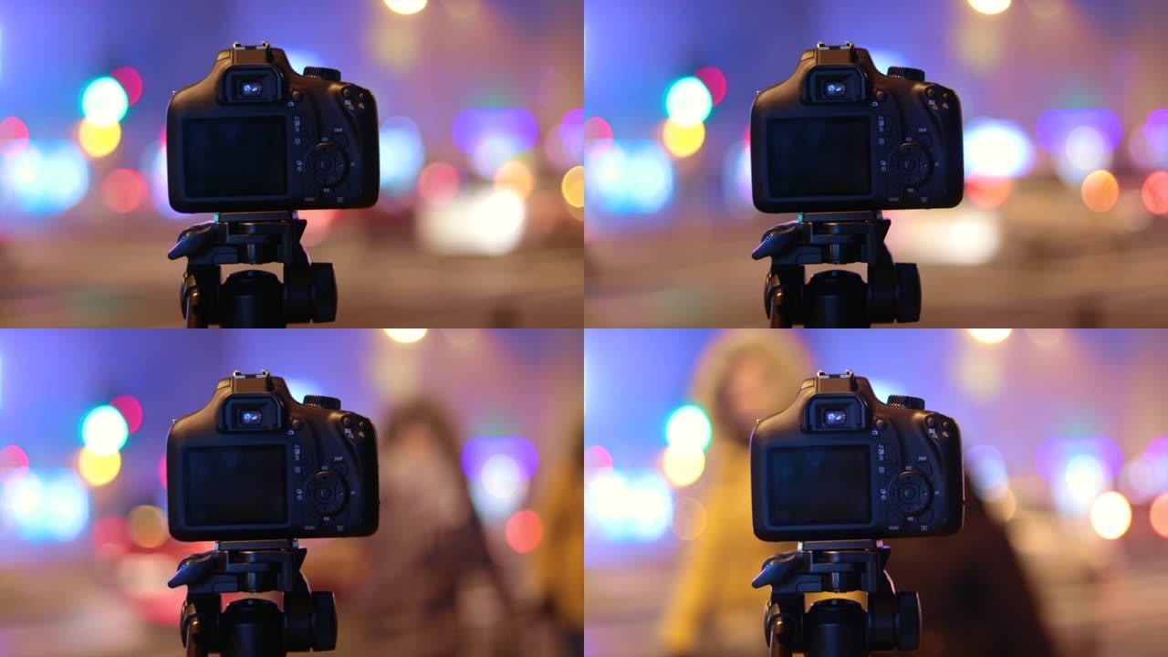 三脚架上的高科技相机记录夜间的城市灯光，汽车和交通工具。