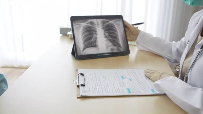专业医生戴外科口罩解释患者，并显示带有肺部x射线图像的屏幕笔记本电脑。内科医生穿着长袍说话疑似患者感