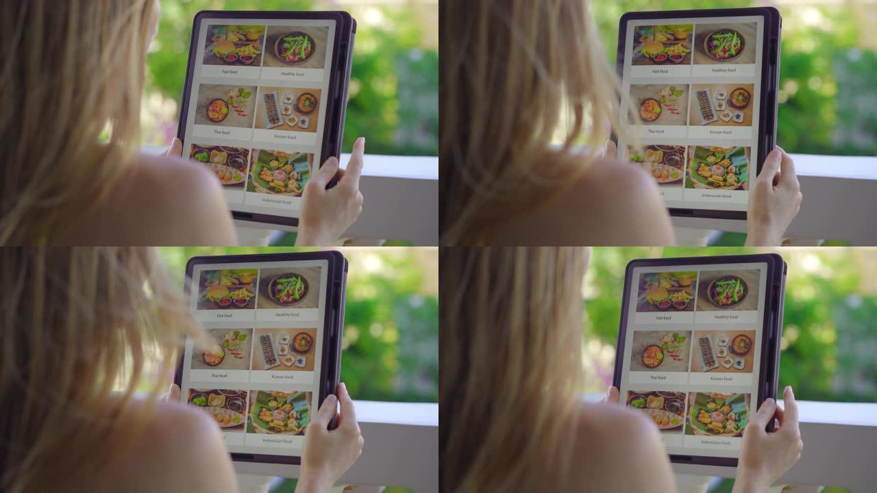 年轻女子用平板电脑在网上订购午餐食物。她坐在公寓的阳台上