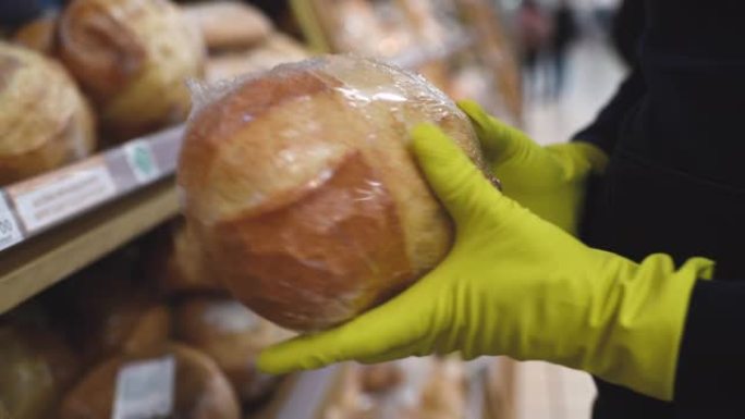 戴着面具和橡胶手套的人在超市里选择面包