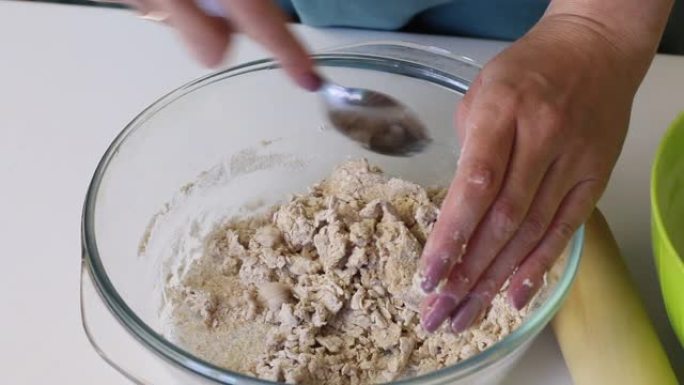 女人做无酵饼的面团。在玻璃容器中混合面粉和水。准备无酵饼
