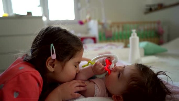 可爱的小女孩在手臂上亲吻她的小妹妹