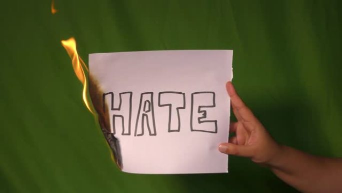 一只手握着燃烧的纸，上面写着仇恨文字。