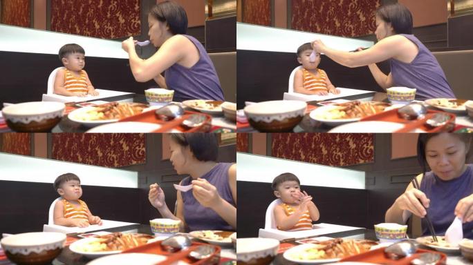 快乐的亚洲母亲和儿子一起在餐馆吃午饭。