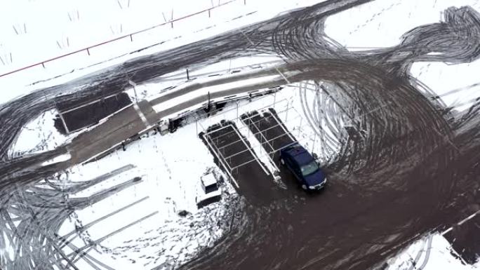 驾驶场地上的无人机俯视图，汽车练习驾驶汽车以获得驾驶执照。冬天下雪的地方进行驾驶练习。车库和停车位的