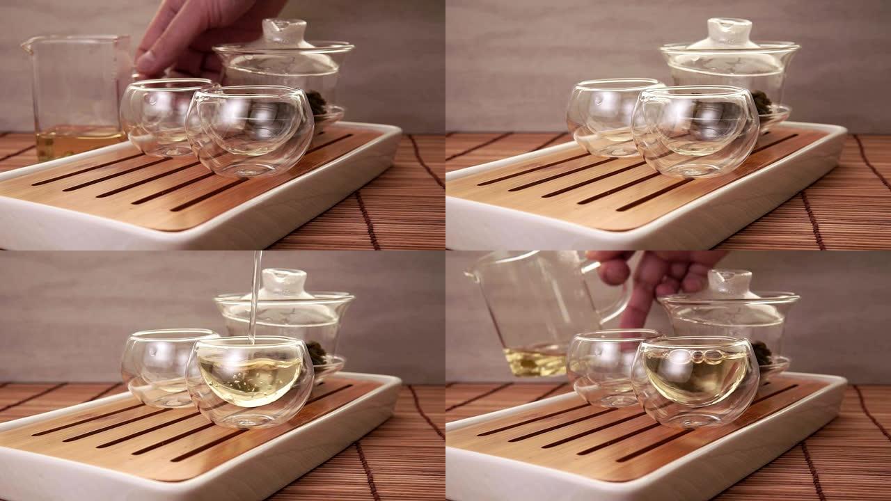 将中国绿茶从玻璃茶壶倒入一个小杯子中
