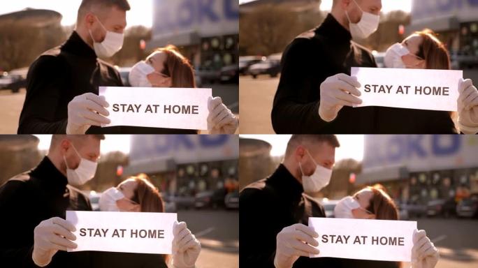 一对戴着医用口罩的夫妇拿着牌子呆在城市街道上的家里。