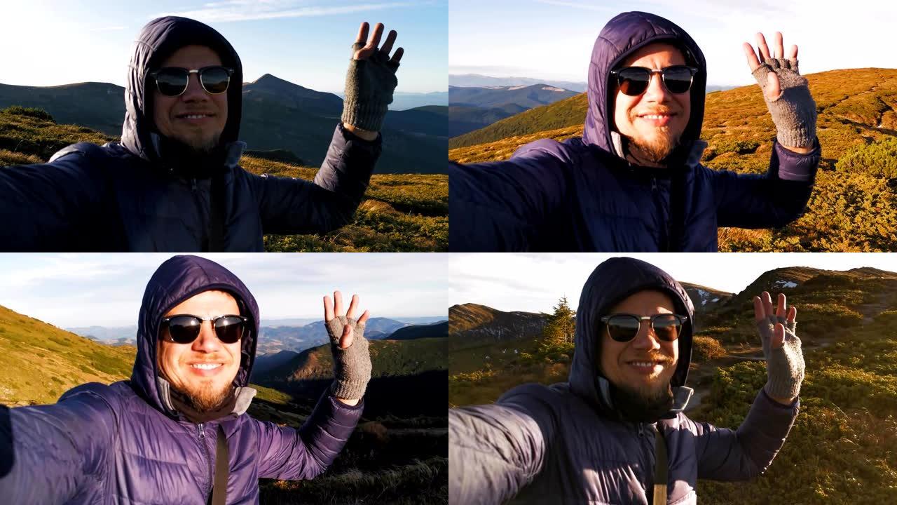 旅行博客作者穿着温暖在山顶上拍摄一个故事。年轻人手里拿着相机，可以看到山顶的景色。乌克兰喀尔巴阡山脉
