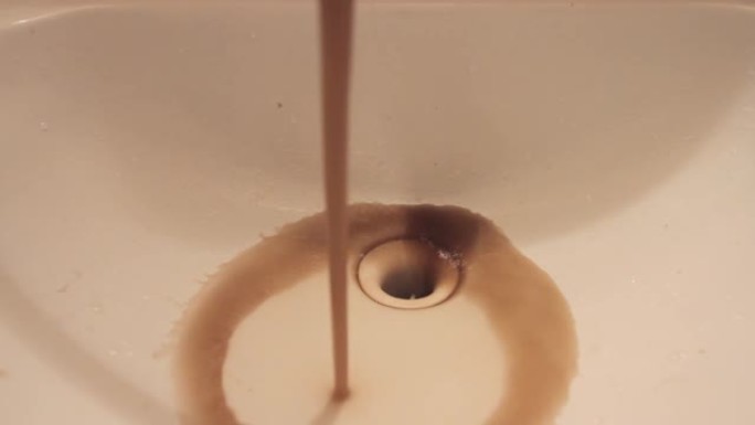 关闭从浴室水槽水龙头流出的肮脏生锈的棕色污水。水流流向下水道。
