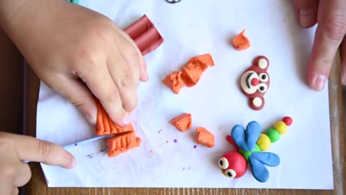 一个小男孩玩橡皮泥。他制作各种小雕塑。