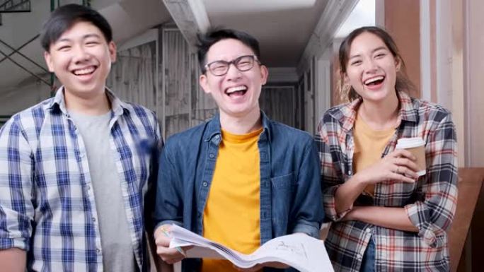 三个亚洲工人朋友站在一起，在房屋装修现场施工背景中充满乐趣和快乐的微笑