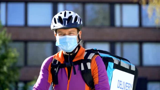 戴着医用口罩和自行车头盔的女快递员的肖像。
