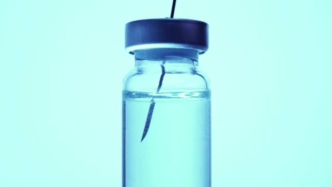 用小瓶的疫苗填充注射器，极端宏观。用无菌医用针头注射器和蓝色冠状病毒疫苗注射剂给药，用于医疗诊所的患