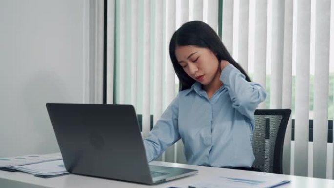 年轻的亚洲妇女坐在公司办公室里，脖子疼。