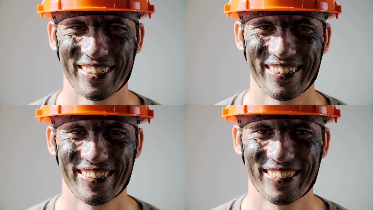 肖像肮脏的矿工。戴着安全帽的美丽白人微笑。肮脏的工作和体力劳动。煤炭开采。工作设备的人。特写。