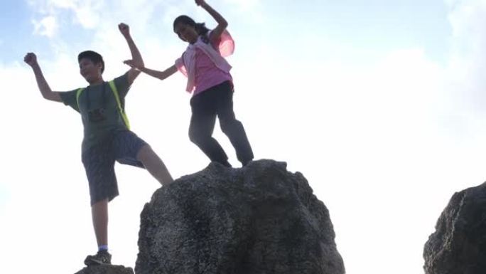 背包客男孩牵着妹妹的手一起爬上石山，生活方式理念。