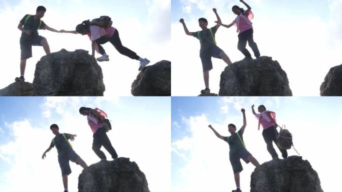 背包客男孩牵着妹妹的手一起爬上石山，生活方式理念。