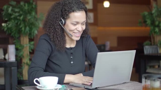 带着笔记本电脑微笑的非裔美国妇女正在进行在线对话