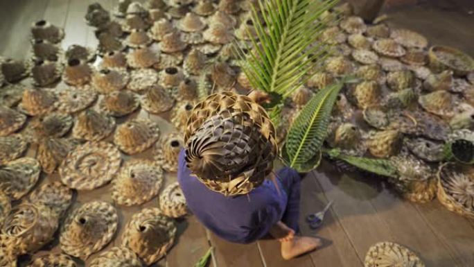 亚洲老妇用天然棕榈树产品的叶子制作泰国当地编织草帽或帽子，泰国。在市场上编织。古老的传统生活方式。