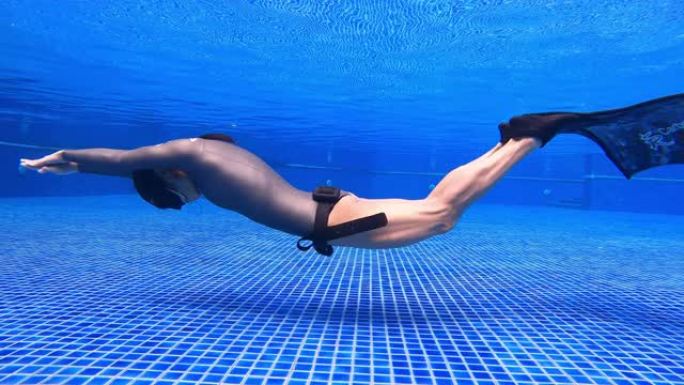 水下特写镜头跟踪女人穿一件长袖比基尼剪裁潜水服做动态呼吸暂停游泳鳍海豚踢单鳍
