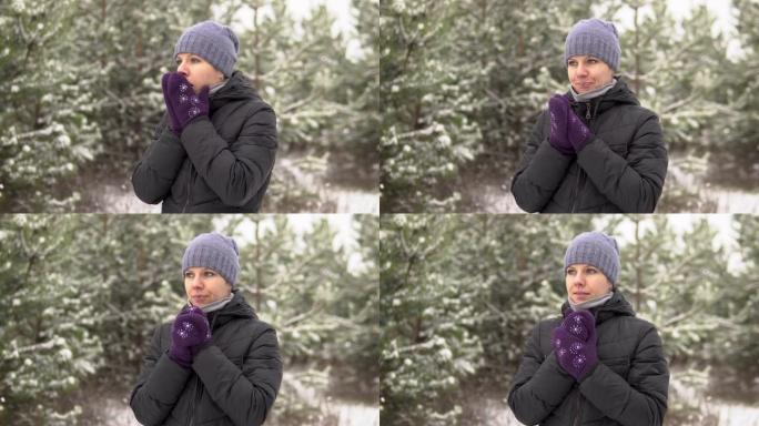 一个女孩在下雪天站在森林或公园里。游客很冷，擦着手咳嗽。
