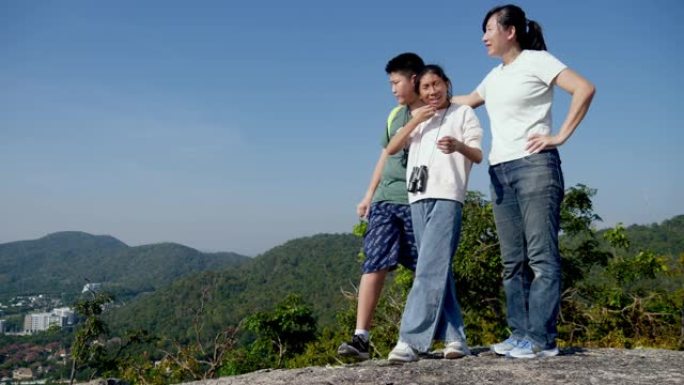 快乐的亚洲单身母亲和她的孩子一起享受山顶景观，冒险概念。