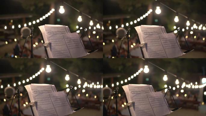 音乐台上的笔记，节日平台中间的麦克风旁边，装饰着灯泡的花环